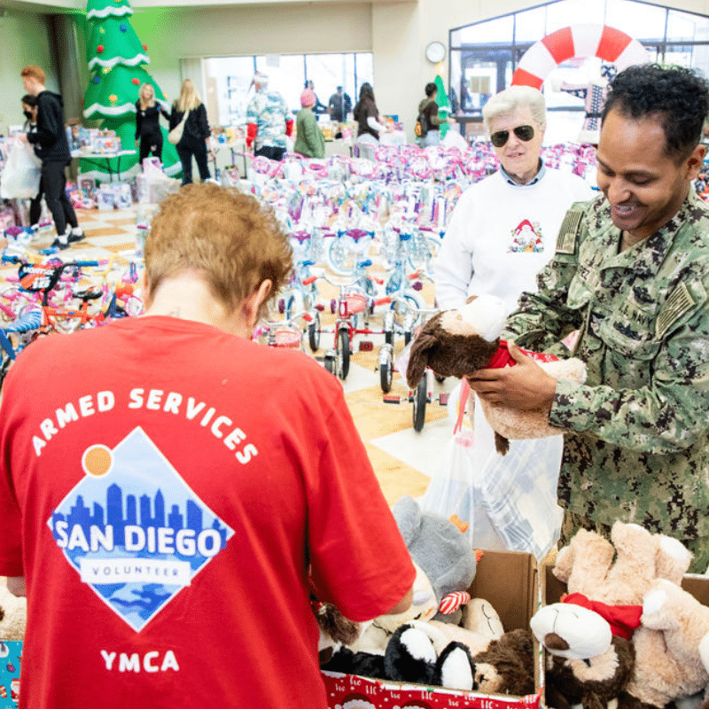 Operation Holiday Joy military dad receives assistance at the toy drive from ASYMCA San Diego volunteer.